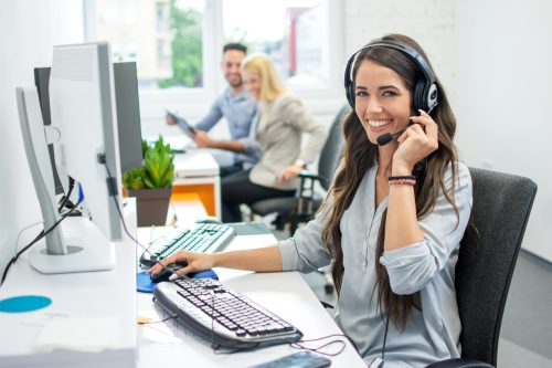 Lächelnde, freundliche Kundenservice-Mitarbeiterin mit Headset, arbeitet am IT-Service und unterstützt Kunden